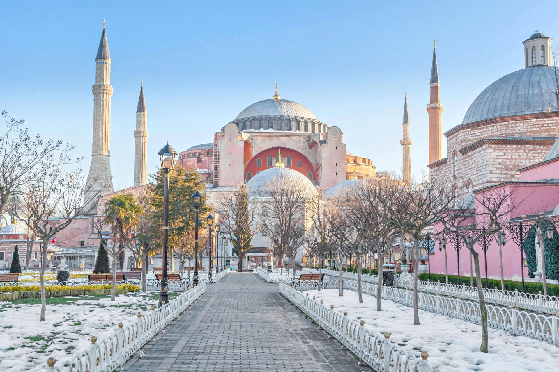 De Hagia Sophia in Istanbul bij zonnig daglicht, met besneeuwde paden en kale bomen in het park ervoor.